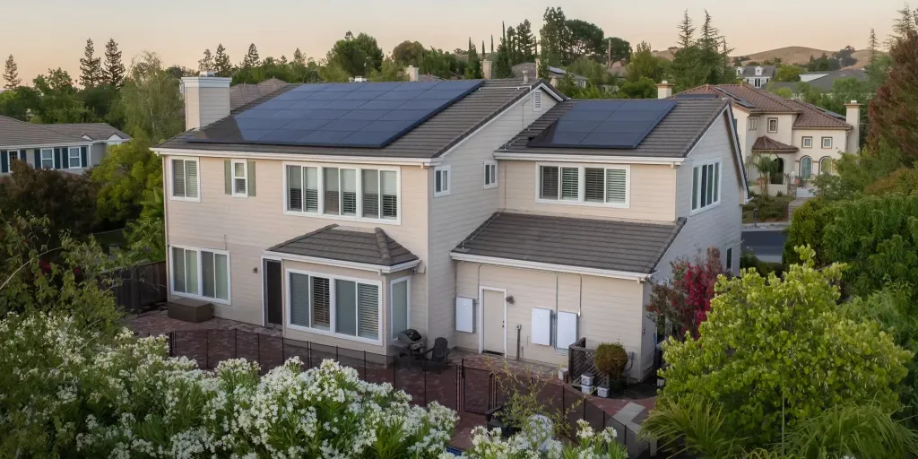 Tesla solar panels on a home roofline with sky background