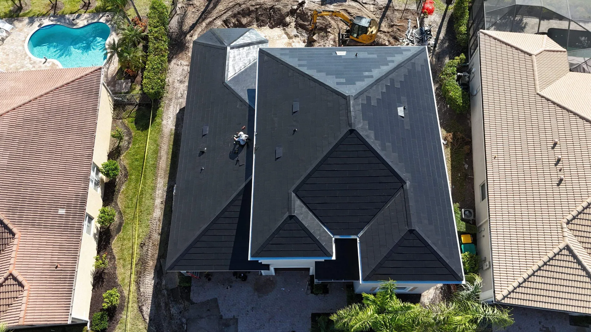 Top down view of a new dark composite roof next to a screened pool