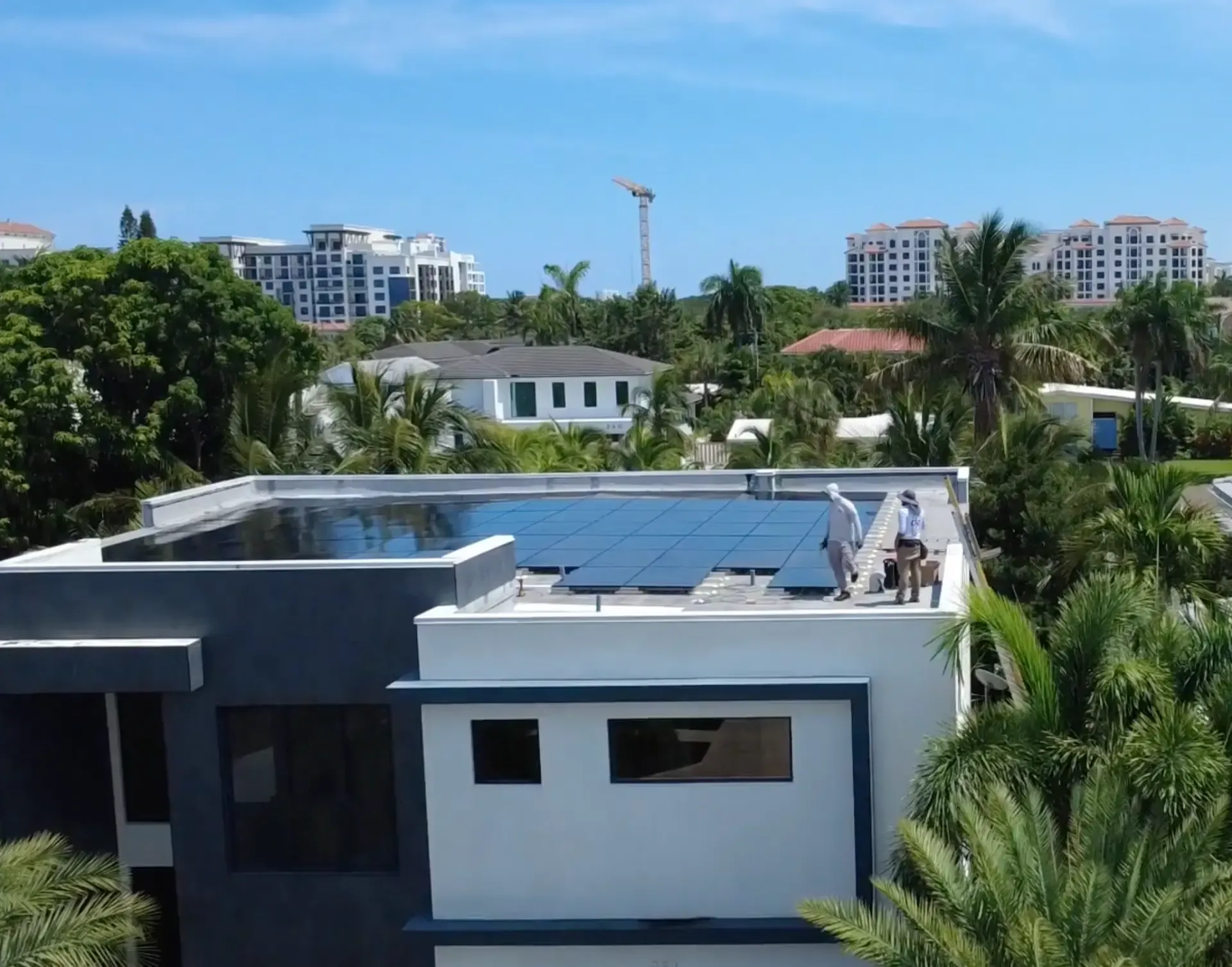 Aerial view of Coastal Energy installers completing a solar panel array on a modern flat roof home in Florida