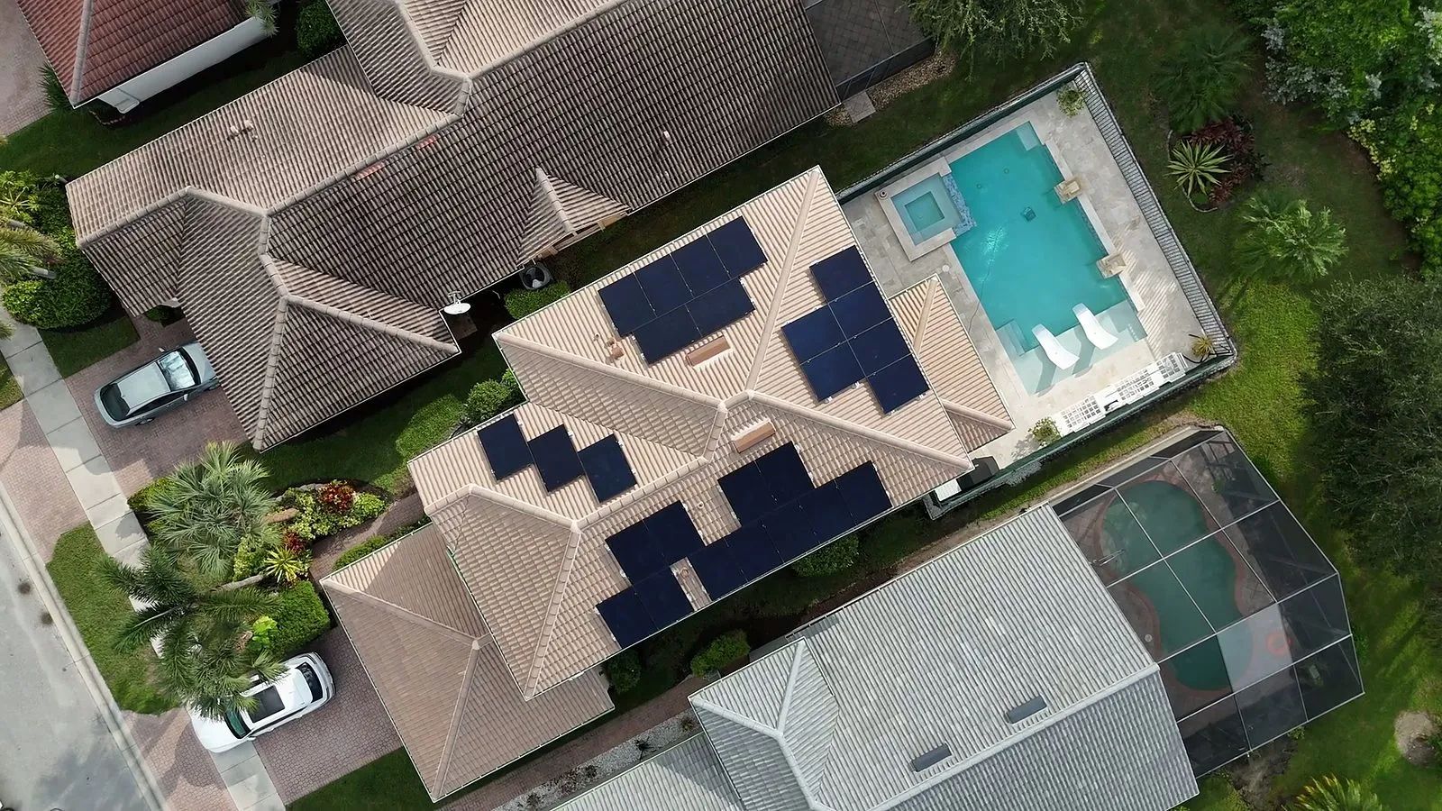 Black solar panels mounted along the tile roofline of a Florida waterfront home, installed by Coastal Energy