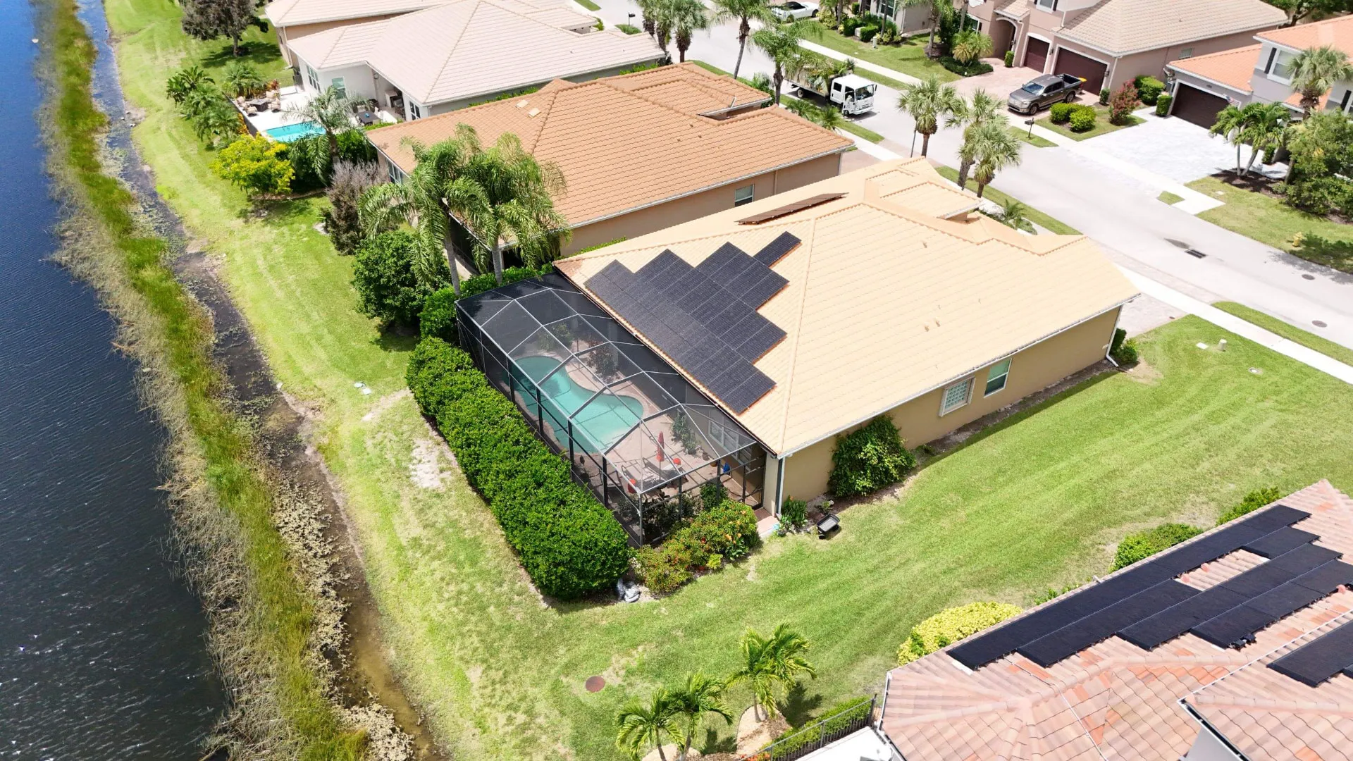 Aerial of a lakefront Florida home with solar panels on a tile roof