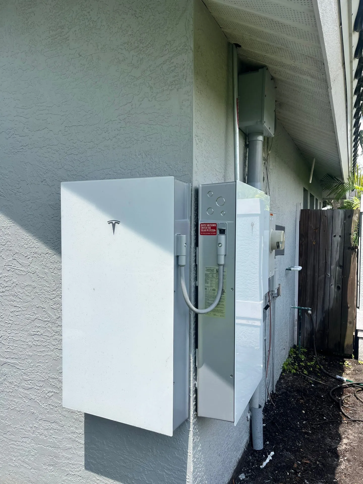 Tesla Powerwall 3 and gateway mounted on the stucco wall of a Florida home