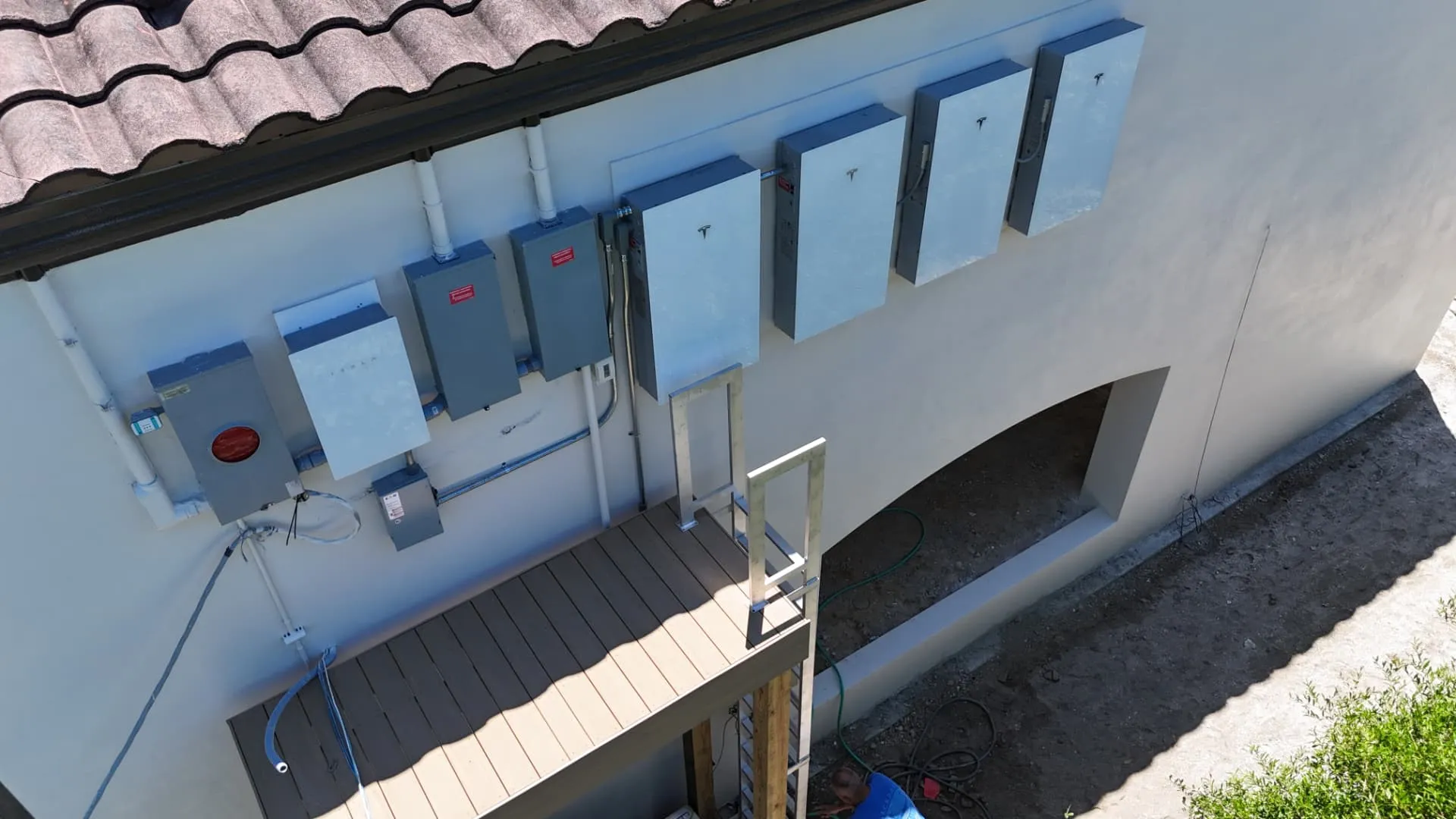 Aerial view of Tesla Powerwalls and electrical gear on a Florida home wall