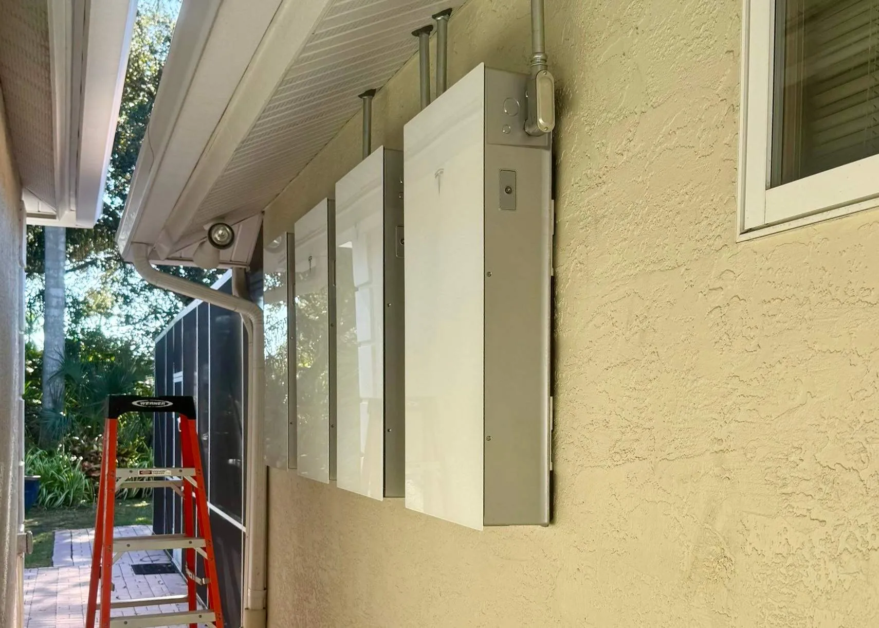 Row of Tesla Powerwalls mounted under a home's soffit