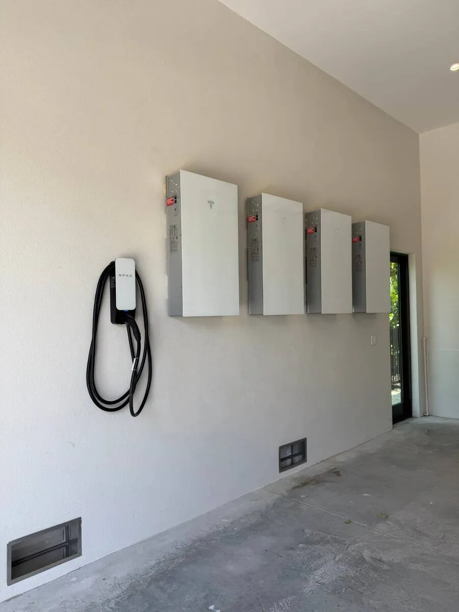 Tesla Wall Connector EV charger installed in a Florida garage beside a Tesla Powerwall