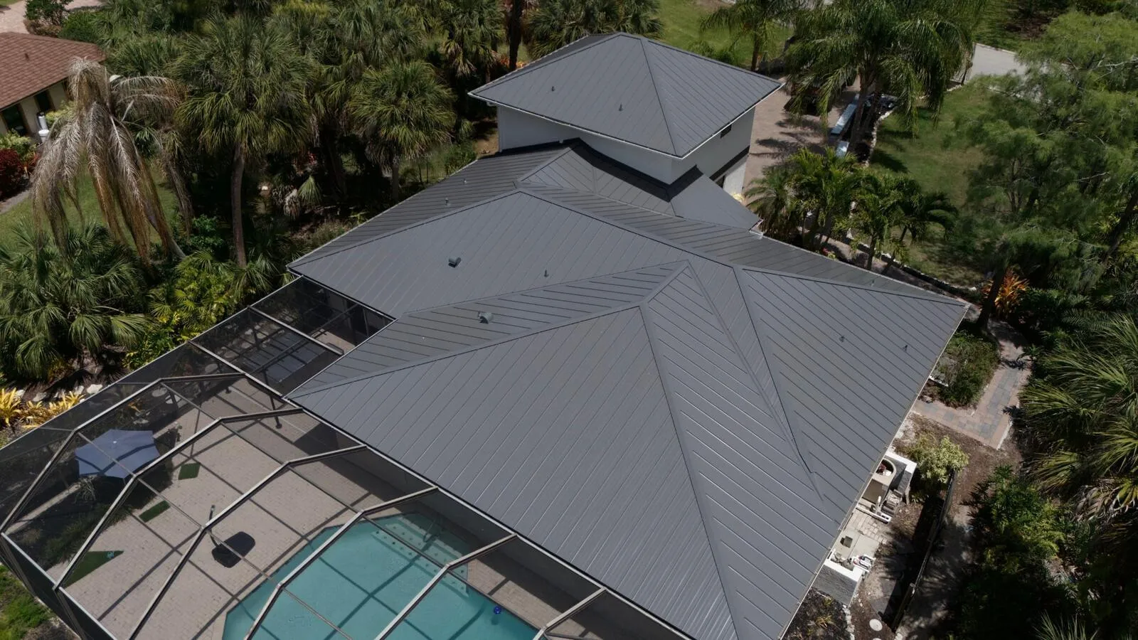 Angled aerial of a new standing seam metal roof above a screened pool cage in Southwest Florida