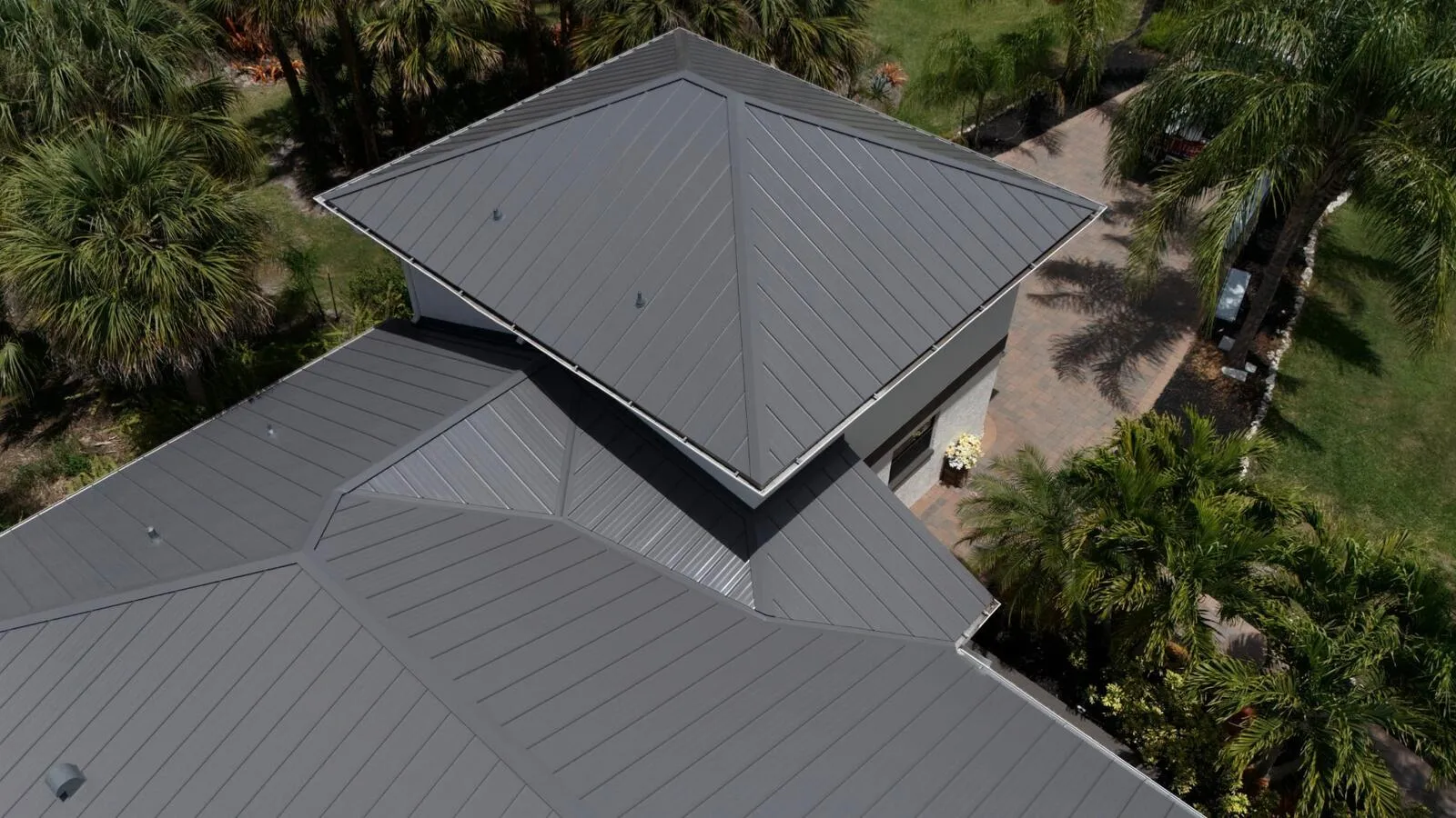 Aerial detail of charcoal standing seam metal roof hips and ridge on a Florida home