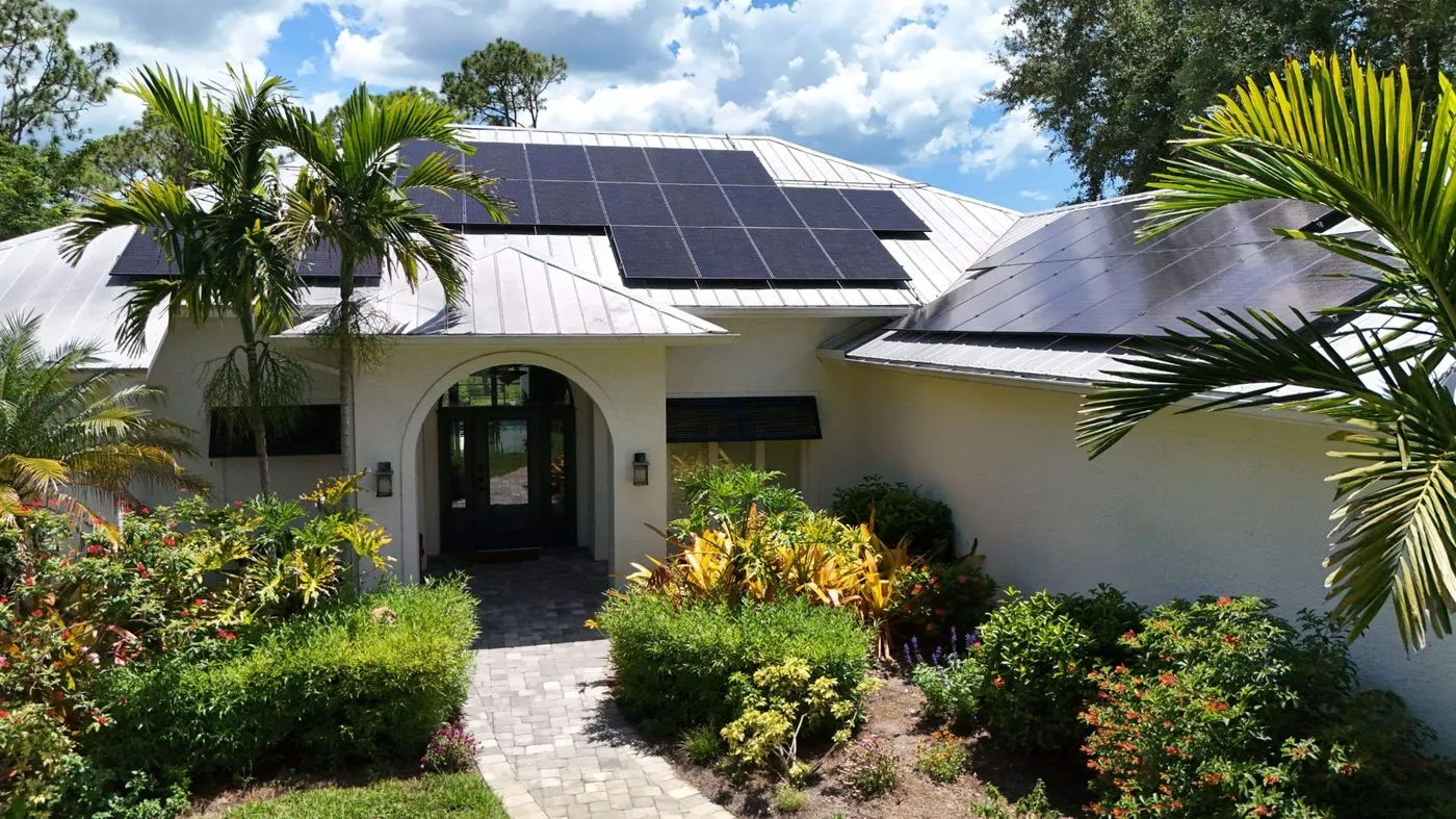 Solar panels on a silver standing seam metal roof over the arched entrance of a Florida home