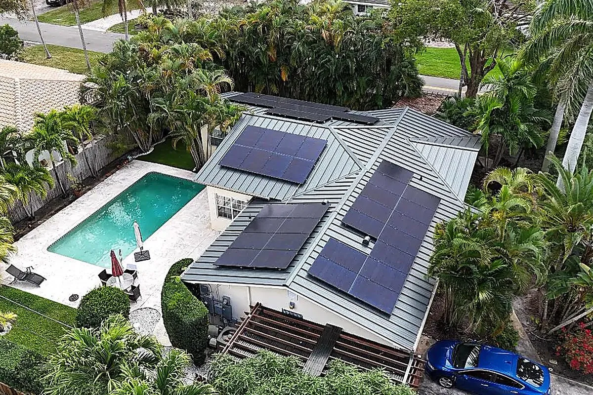Aerial view of a completed solar array on a gray standing seam metal roof of a Florida home