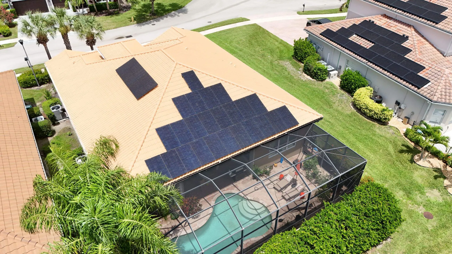 Aerial of a large solar array on a tile roof over a screened pool home in Florida