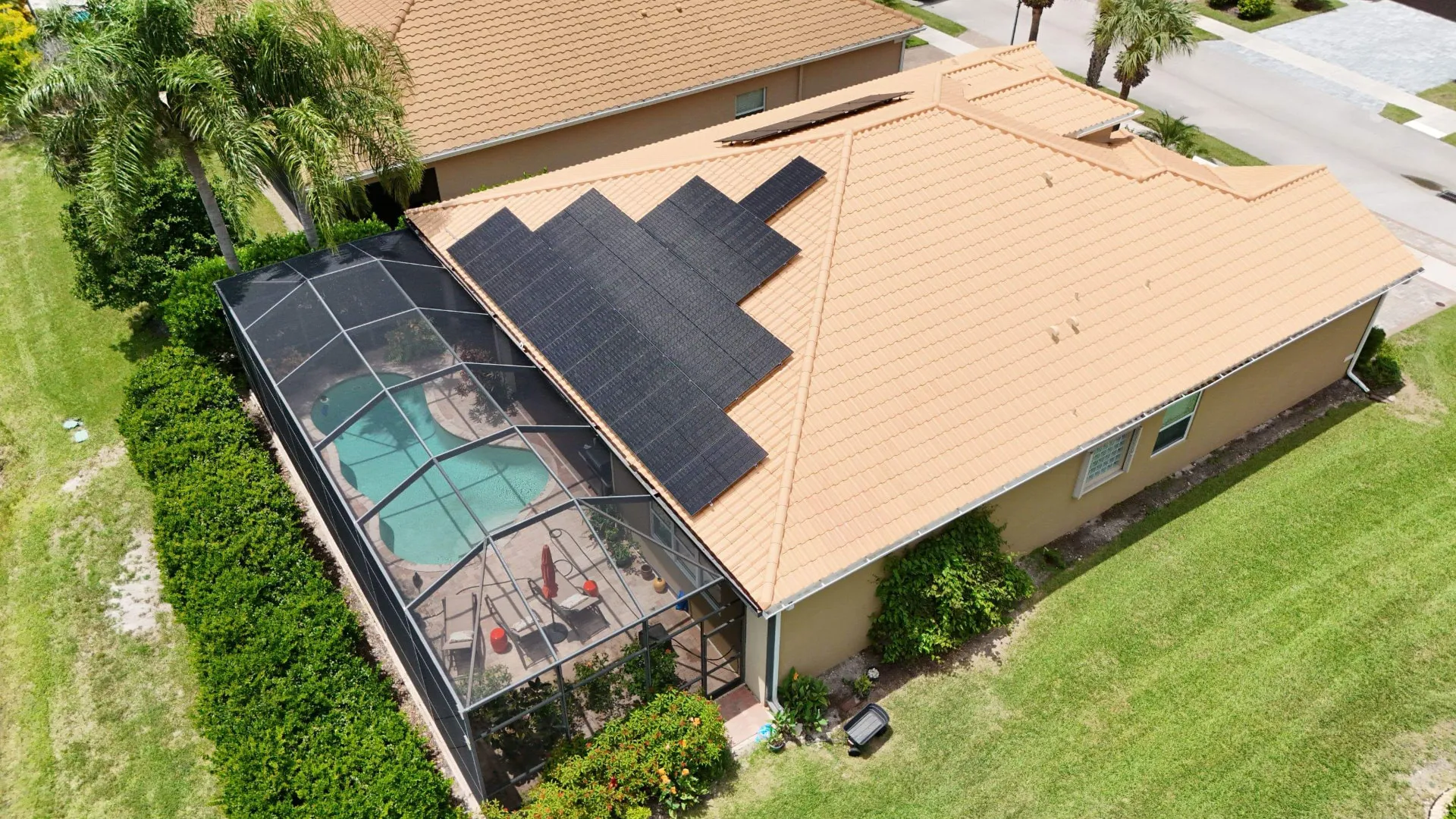 Aerial of a tile roof solar array above a screened pool enclosure in Florida
