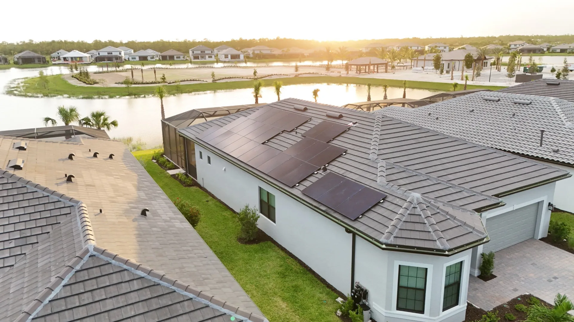 All black solar panels on a gray tile roof of a Florida lakefront home at sunset, installed by Coastal Energy