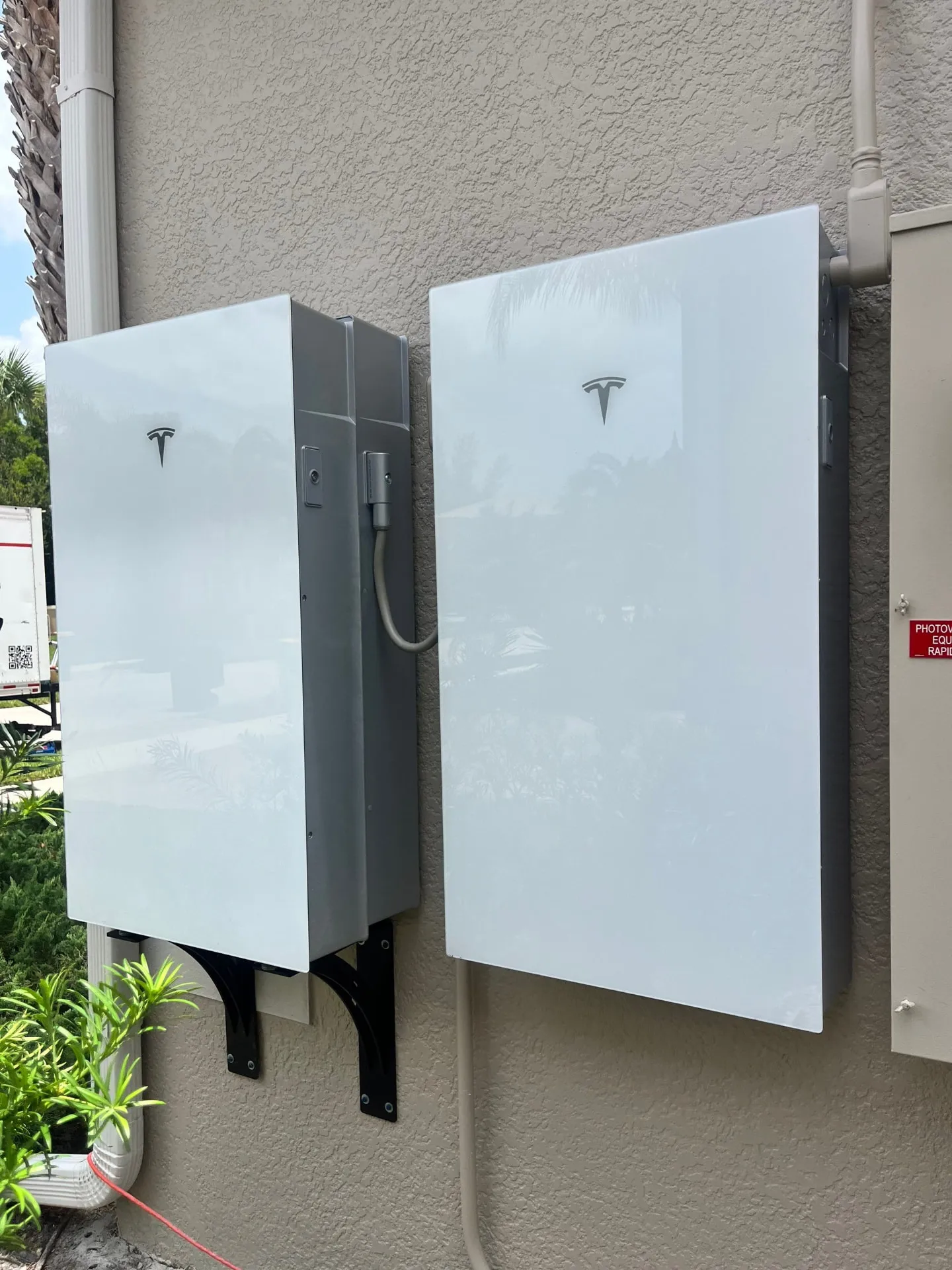 Two Tesla Powerwall batteries mounted on the exterior stucco wall of a Lehigh Acres, Florida home